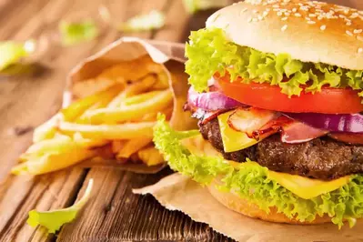 burger topped with lettuce, tomato, bacon, and cheese served with fries