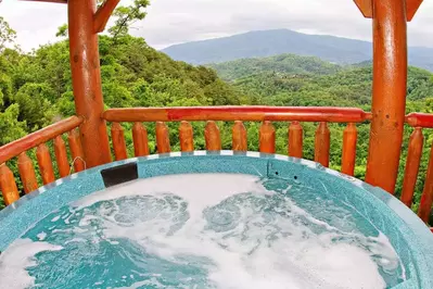 hot tub on the deck of a cabin with a mountain view in pigeon forge